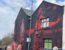 a mural of mo salah with his arms outstretched on the side of a house close to anfield