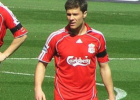 xabi alonso in liverpool kit on the pitch with part of the centre circle in the background and dirk kuyt's arm poking into the lefthand side of the picture