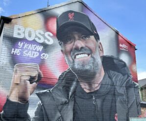 mural of jurgen clop on the side of a house near anfield. klopp is wearing a baseball cap and punching the air with the words 'boss, you know he said so' written to the side.