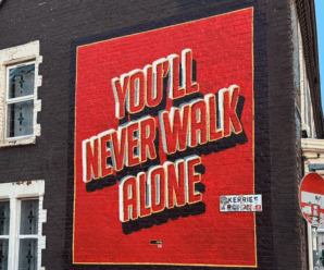 a mural on a black wall near anfield that shows a red box with the words you'll never walk alone written inside